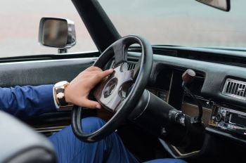 The driver's hands on the steering wheel of a retro car