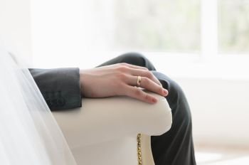 hand of the groom with a ring on the chair in front of a window