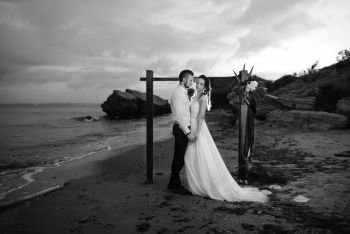 young couple groom and bride with a bouquet in the evening on the beach near the wedding arch