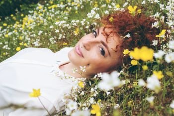 Beautiful redhead woman in a field of flowers 