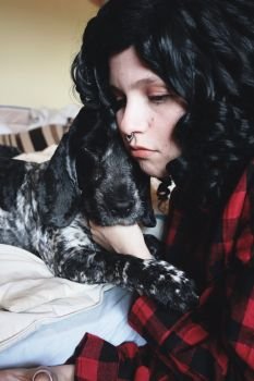 Young brunette woman hugging her dog 