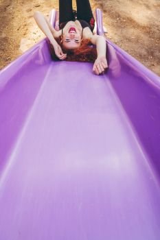 young redhead woman having fun in a slide 
