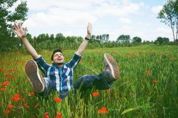 Man enjoying the day in a field of green wheat and flowers 