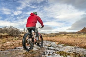 a male riding a fat bike across a stream in Red Mountain Open Space, Colorado , late fall scenery