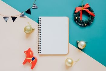Creative flat lay of craft and blank notebook mock up with christmas ornaments on colorful background, minimal style