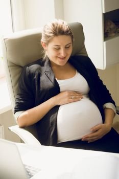 Smiling pregnant businesswoman sitting on chair at office