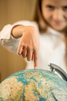 Little girl holding index finger on Earth globe