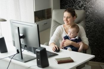 Mother with her baby son in office using computer