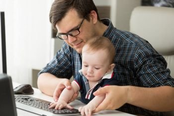 Father working at home with his little baby boy