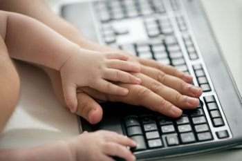 Closeup of fathers and baby’s hands on computer keyboard