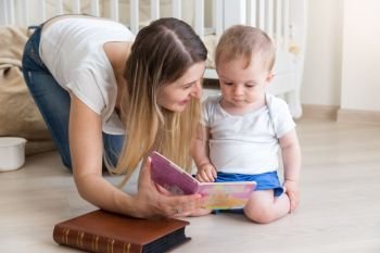 Mother reading book to her 10 months old baby boy on floor at living room