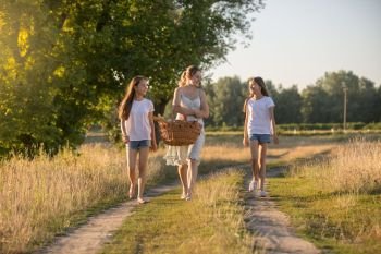 Young mother walking to picnic with her two daughter