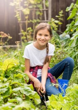 Happy smiling teenage girl planting lettuce at garden at sunny day