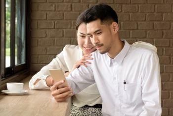 Beautiful cute love couple looking at smartphone together