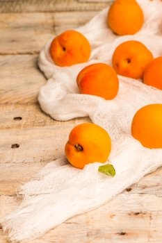 Fresh apricots and white cloth over wooden table background.