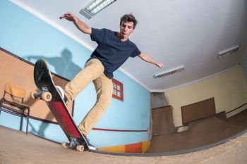 Skateboarder performing a blunt to fakie on a mini ramp at indoor skate park.