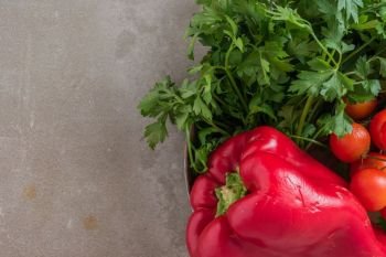 Red bell pepper, cherry tomatoes and  parsley on concrete background.