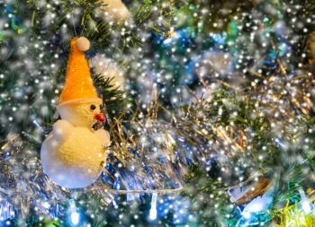 Decorated snowman on Christmas tree with snowfall