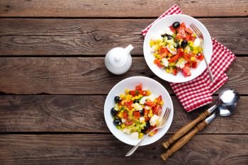 Fresh vegetable salad bowls of tomatoes, corn, pepper, olives, celery, green onion and feta cheese. Healthy food. Diet dinner or lunch menu. Salad plate on table. Flat lay. Top view