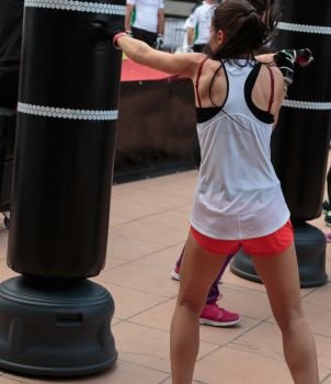 Young Girl with Shorts and White Tank Top: Fitness Boxing Workout with Punching Bag. Young Girl with Shorts and White Tank Top: Fitness Boxing Workou