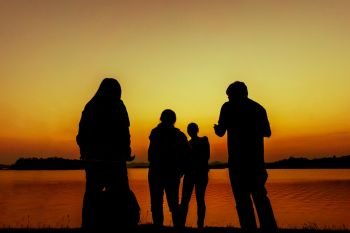 The silhouette of group of peoples near the water during sunset time

