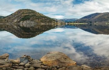 Norwegian autumn landscape a€“ fjord with reflection of mountains and sky in clear water