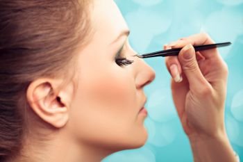 Make-up artist extending model’s lashes, focus on  lashes