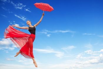 Young Elegant Woman Flying in the Sunny Blue Sky in the Black Gymnastics Leotard , Red Long Skirt with Red Polka Dot Umbrella