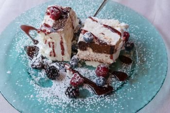 Sweet meringue cake(Pavlova) with fresh winter berry fruits on glass plate.