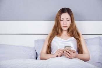 woman using her smartphone on bed in the bedroom