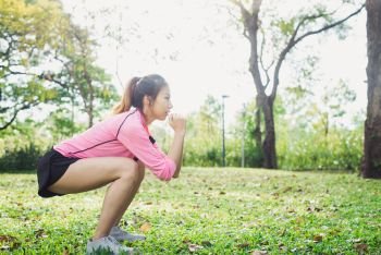Young asian woman do squats for exercise to build up her beauty . Young asian woman do squats for exercise to build up her beauty body in park environ with green trees and warm sunlight in the afternoon. Young woman workout exercise at the park. Outdoor exercising.