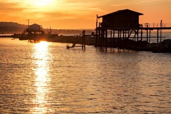 Stilt house over the sea at sunset with the sun reflecting on the water. Stilt house over the sea at sunset