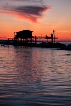 Stilt house in silhouette over the sea in a beautiful red sunset. Stilt house in silhouette over the sea