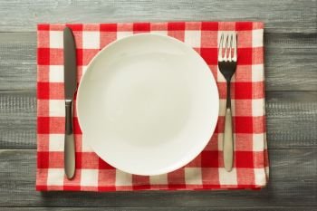 plate, knife and fork on rustic wooden background