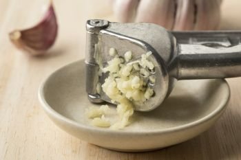 Fresh garlic clove crushed in a press