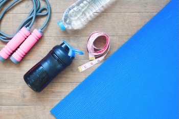 Sport and yoga equipments with measuring-tape on wooden background with copy space