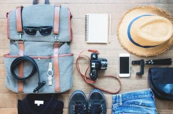 Overhead shot of essentials for traveler. Outfit of young man traveler, camera, mobile device, sunglassses. Travel concept