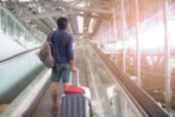Blurred background airport interior with the passenger dragging luggage suitcase