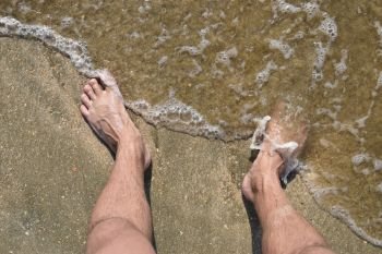 Legs men on the sea sand near sea wave. Walk on the beach.. Legs men on the sea sand near sea wave