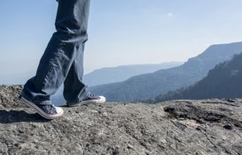  Man walking on edge of a cliff mountain top , travel concept