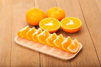orange fruit in wooden plate on wood background