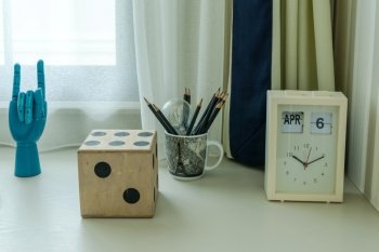 decorative table with pencils and clock in room