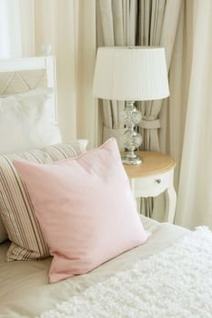 luxury bedroom interior with pink pillows and reading lamp on bedside table