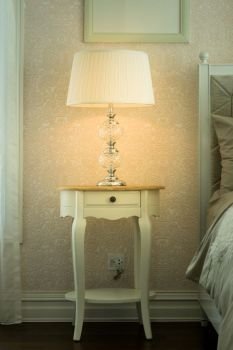 white lamp on bedside wooden table in luxury bedroom