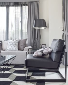 Black armchair with geometric rug in modern living corner