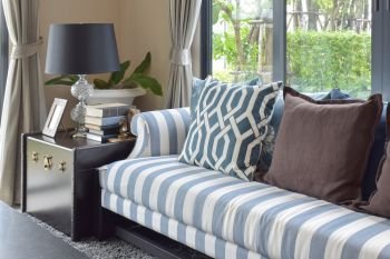 blue pattern pillows on striped sofa with black lamp in living room at home