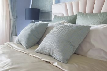 Satin finished pillows setting on bed 