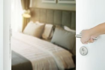 man hand opening white door to modern bedroom interior