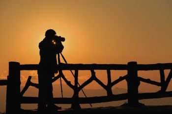 silhouette of a photographer who shoots a sunset in the mountains