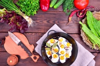 Fried egg and fresh vegetables and herbs on a wooden background, top view, empty space in the middle
